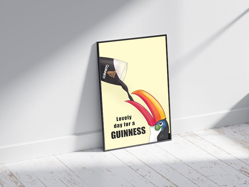 K&ouml;nnte beinhalten: Ein schwarzer gerahmter Poster mit gelbem Hintergrund. Ein Tukan mit rotem und orangefarbenem Schnabel trinkt aus einem Glas Guinness-Bier. Der Text auf dem Poster lautet "Lovely day for a GUINNESS".