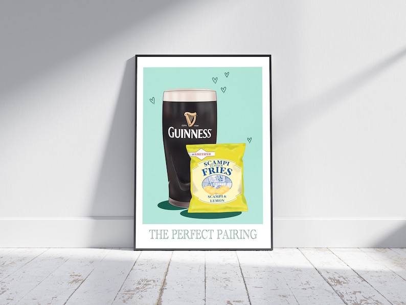 May include: A framed print depicting a pint of Guinness and a packet of Scampi Fries. The Guinness glass is black with the brand's logo. The yellow bag of crisps has a blue and white design. The text at the bottom reads "THE PERFECT PAIRING."