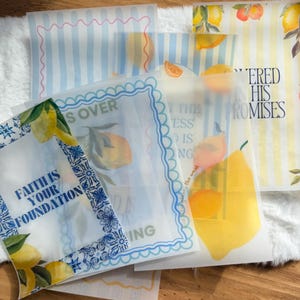 May include: A collection of translucent paper sheets with lemon and citrus fruit illustrations. Some sheets feature text like "Faith is Your Foundation" and "He Covered His Promises". Designs include blue stripes and decorative borders.