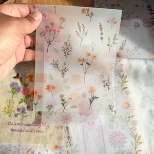May include: A collection of floral-themed paper sheets. The sheets feature various flower illustrations in shades of pink, orange, and purple. Some sheets have text that reads "The LORD makes everything beautiful in it's time."