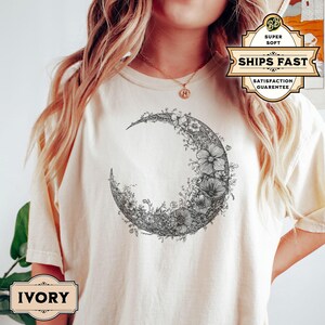 Black and white floral crescent moon design on a minimalist boho t shirt, showcasing delicate nature inspired linework that forms an elegant lunar shape perfect for astrology lovers and those seeking celestial style.