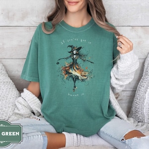 A spooky yet chic t-shirt design featuring a dancing skeleton girl in a flowing gown, holding a jack-o-lantern, with the phrase If You've Got It, Haunt It. Perfect for Halloween enthusiasts, gothic fashion fans, and stylish Halloween events.