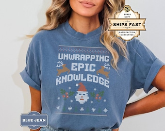 May include: A blue jean t-shirt with a Christmas-themed design featuring a Santa Claus, reindeer, and the text "Unwrapping Epic Knowledge".