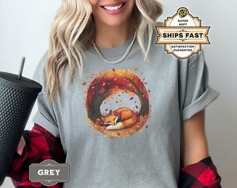 May include: A grey t-shirt with a graphic of a fox sleeping in a circle of autumn leaves. The text "SHIPS FAST" is on a brown tag.