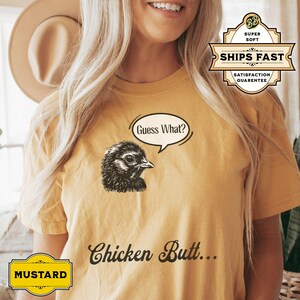 May include: A yellow t-shirt with a black and white illustration of a chicken with the text "Guess What? Chicken Butt..." printed on the front.