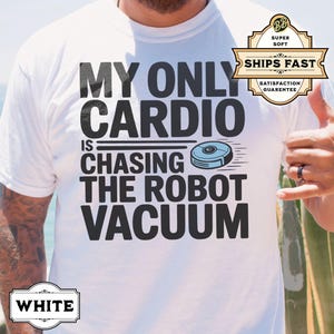 May include: White t-shirt with black text that reads "My only cardio is chasing the robot vacuum". A small blue robot vacuum cleaner is pictured next to the text.