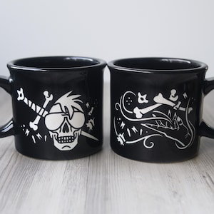 May include: A white ceramic mug with a black handle and the text "But First, Coffee" in a handwritten style. The mug is on a white surface. The mug is approximately 4 inches tall.