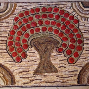 May include: A brown and beige rug with a woven design of a stylized tree with red berries. The rug has a fringed border.