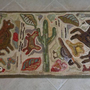 May include: A beige hooked rug with a whimsical design featuring brown animals, a cactus, and leaves. The animals are stylized and have a folk art aesthetic.