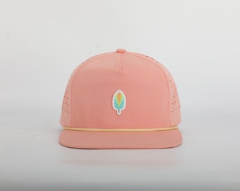May include: A pink and yellow baseball cap with a colorful leaf logo. The cap has a mesh back and a yellow brim.