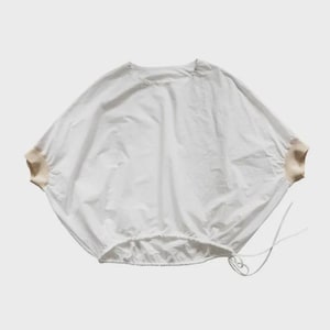May include: White, loose-fitting top with a round neckline and long, wide sleeves. The sleeves have tan-colored cuffs. The bottom hem has a drawstring. The top is made of a lightweight fabric.
