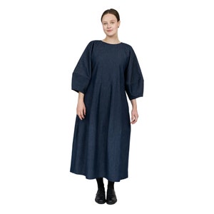 May include: A dark blue denim dress with a loose, flowing silhouette and a round neckline. The dress has three-quarter sleeves and a gathered skirt.