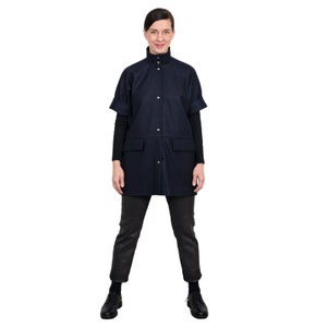 May include: A navy blue short-sleeved collared jacket with a high neckline and button closure. The jacket has two pockets and a relaxed fit.