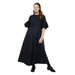 May include: A black maxi dress with puffed sleeves and a round neckline. The dress is made of a lightweight fabric and has a flowy silhouette.