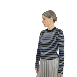 May include: A woman wearing a blue and black striped long-sleeve shirt with a grey skirt.