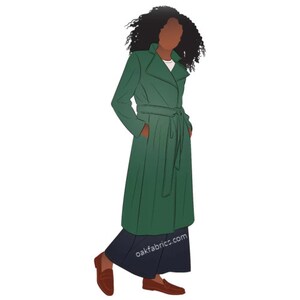 May include: A woman wearing a long, green belted coat with a white shirt underneath. She is wearing brown loafers and has curly dark hair.