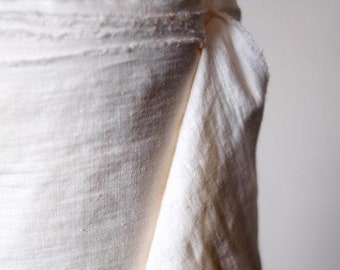 May include: Close-up of a roll of off-white linen fabric. The fabric has a slightly textured surface and is folded in half.