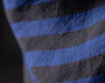 May include: Close-up of a fabric with alternating horizontal stripes in shades of blue and black. The fabric appears to be soft and textured, with a slight sheen. The stripes are evenly spaced and create a bold pattern.