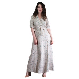 May include: A long-sleeved, beige dress with a white and blue floral print. The dress has a collared neckline, a belt, and a button closure.