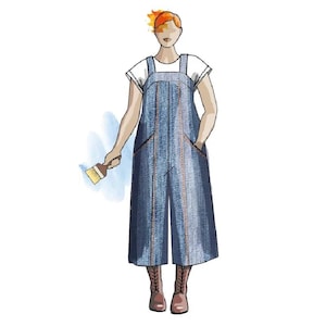 May include: A woman wearing a denim overall dress with a white t-shirt and brown boots. She is holding a paintbrush.