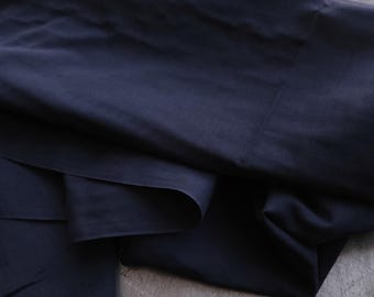May include: A dark blue fabric folded on a gray surface. The fabric is smooth and has a slight sheen.