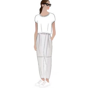 May include: A white cropped t-shirt with a round neckline and short sleeves. The model is wearing white pants with a wrap-style design and a belt.