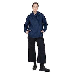 May include: A navy blue linen shirt with a tie detail at the neck. The shirt is worn with black wide-leg pants and black ankle boots.