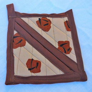 Two cinnamon roll potholder hand quilted mitts.  Double-layered potholder designed for hand insertion and hook for hanging.