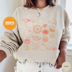 a woman wearing a sweatshirt with oranges on it