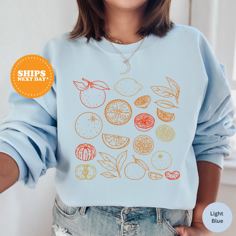 a woman wearing a blue sweatshirt with oranges and lemons on it