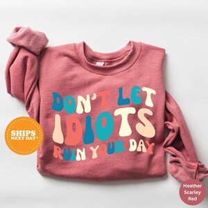 a pink shirt with the words don't let idiots run your day on it