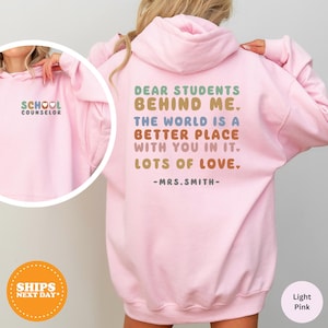 a girl wearing a pink sweatshirt with the words dear students behind her