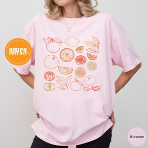 a woman wearing a pink shirt with oranges on it