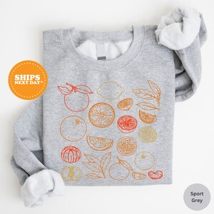 a gray shirt with oranges and lemons on it