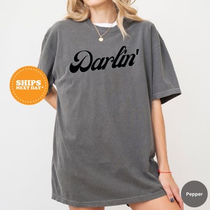 a woman wearing a gray shirt with the word darbin on it
