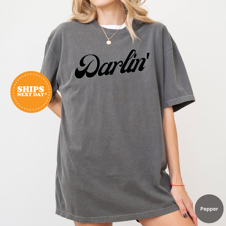 a woman wearing a gray shirt with the word darbin on it