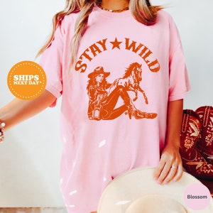 a woman wearing a pink shirt that says stay wild