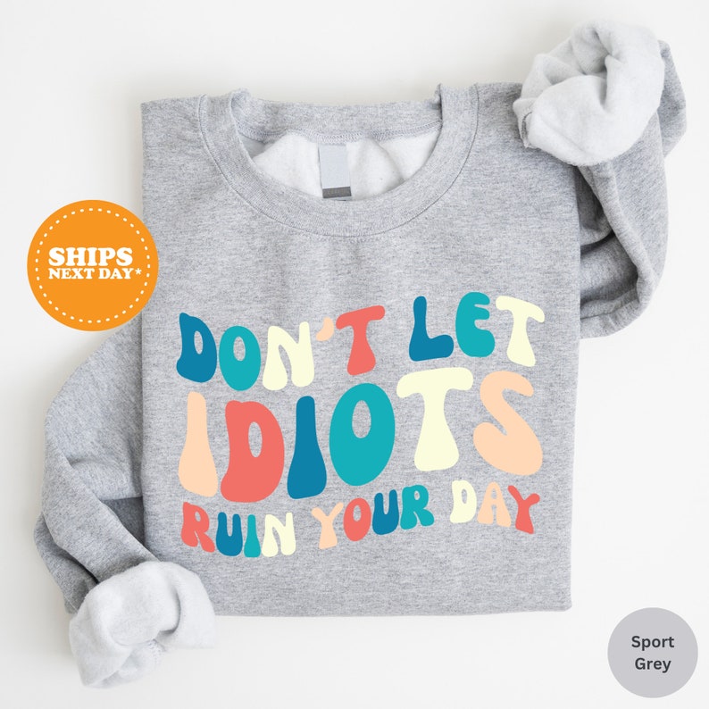 a gray shirt with the words don't let idiots run your day on it