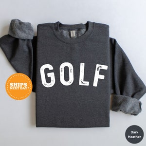 Puede incluir: Sudadera gris oscuro jaspeada con la palabra "GOLF" impresa en blanco en la parte delantera.