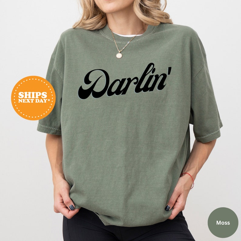 a woman wearing a green shirt with the word darfin on it