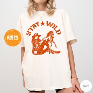 a woman wearing a t - shirt that says stay wild