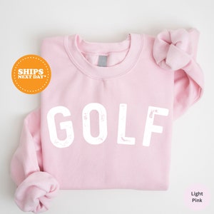 a pink shirt with the word golf printed on it