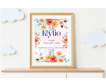 May include: A framed print featuring the name "Kylie" in navy blue script, surrounded by watercolor floral arrangements in orange, yellow, and blue. The print includes the origin and meaning of the name.