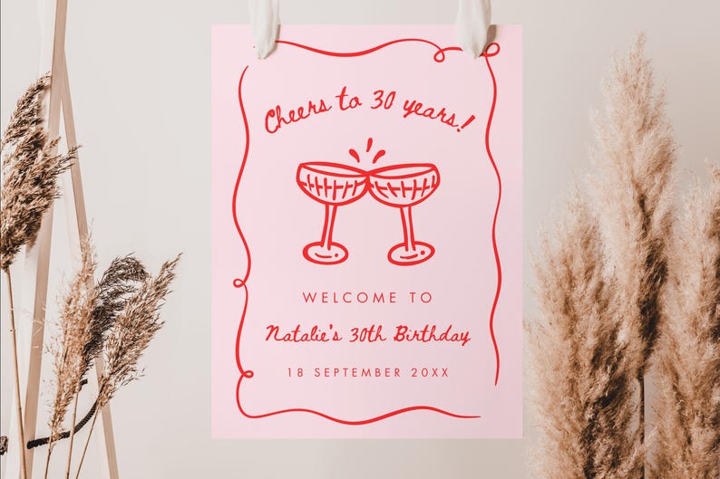 May include: A pink birthday sign with red text and a decorative border. The sign reads "Cheers to 30 years!" and "Welcome to Natalie's 30th Birthday, 18 September 20XX." Two champagne glasses are illustrated above the text.