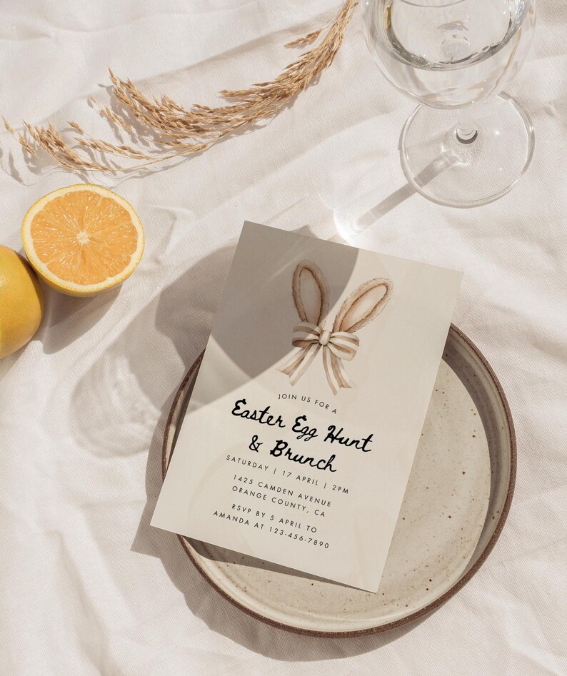 May include: A beige invitation card with a watercolor illustration of a bunny's ears and a bow. The text on the card reads "Join us for a Easter Egg Hunt & Brunch" with the date, time, address, and RSVP information.