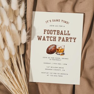 May include: A white card with brown text announcing a football watch party. The card features a watercolor illustration of a football and a glass of whiskey. The text reads "It's Game Time! Join us for a Football Watch Party. Join us for food, drinks & football. Sunday 9th Feb | 2PM. 147 Willow Drive Orange County, CA. RSVP by 1st Feb to Monica at 123-456-7890."