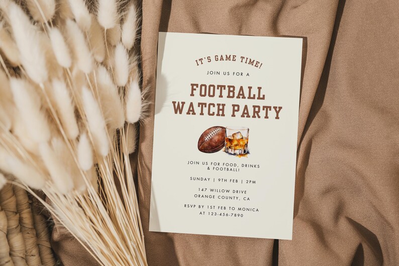 May include: A white card with brown text announcing a football watch party. The card features a watercolor illustration of a football and a glass of whiskey. The text reads "It's Game Time! Join us for a Football Watch Party. Join us for food, drinks & football. Sunday 9th Feb | 2PM. 147 Willow Drive Orange County, CA. RSVP by 1st Feb to Monica at 123-456-7890."