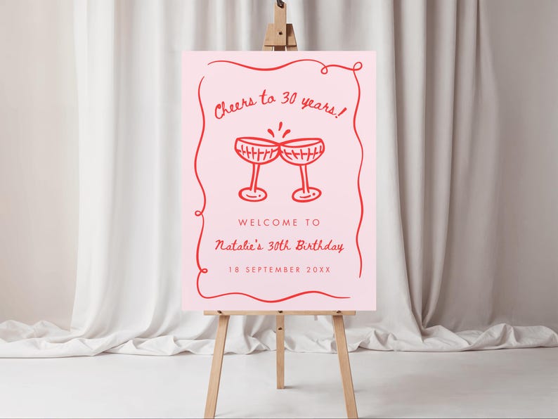 May include: A pink sign on a wooden easel with red text and illustrations. The sign reads "Cheers to 30 years!" and "Welcome to Natalie's 30th Birthday" with the date "18 September 20XX". Two red champagne glasses are illustrated.