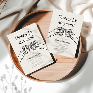 May include: Two white cards with black text and illustrations of hands holding up glasses of alcohol. The text on the cards reads "Cheers to 40 years!" and "Join us to celebrate John's 40th birthday".