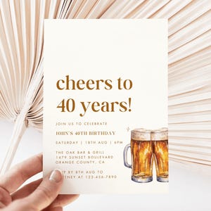 May include: A cream-colored invitation card with the text "cheers to 40 years!" in brown. The card also includes details for a birthday celebration and a watercolor illustration of two beer mugs.